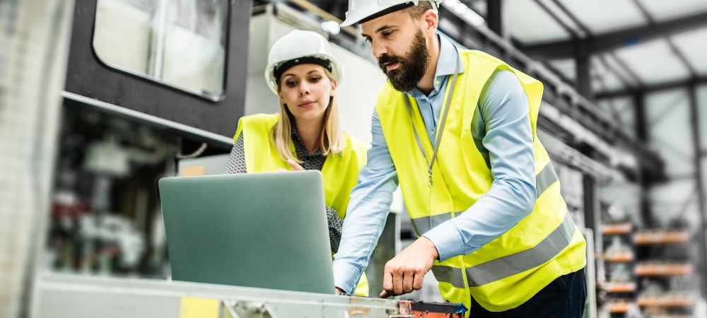 Two workers reviewing manufacturing company marketing on a laptop