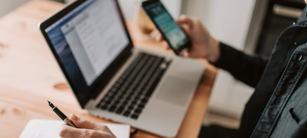 B2B marketing manager reviewing information on a laptop and mobile device to help make complex business decisions