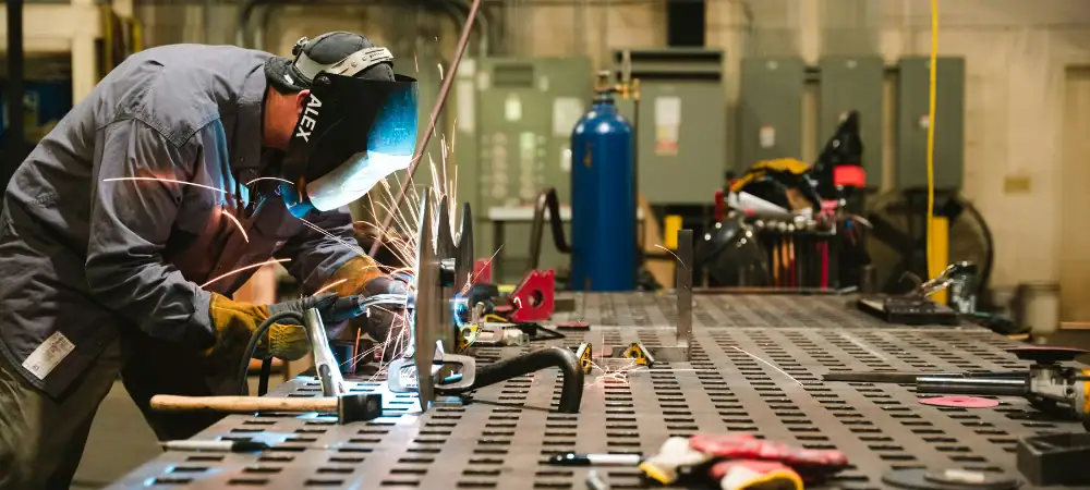 Worker welding metal in industrial workshop for manufacturing marketing companies